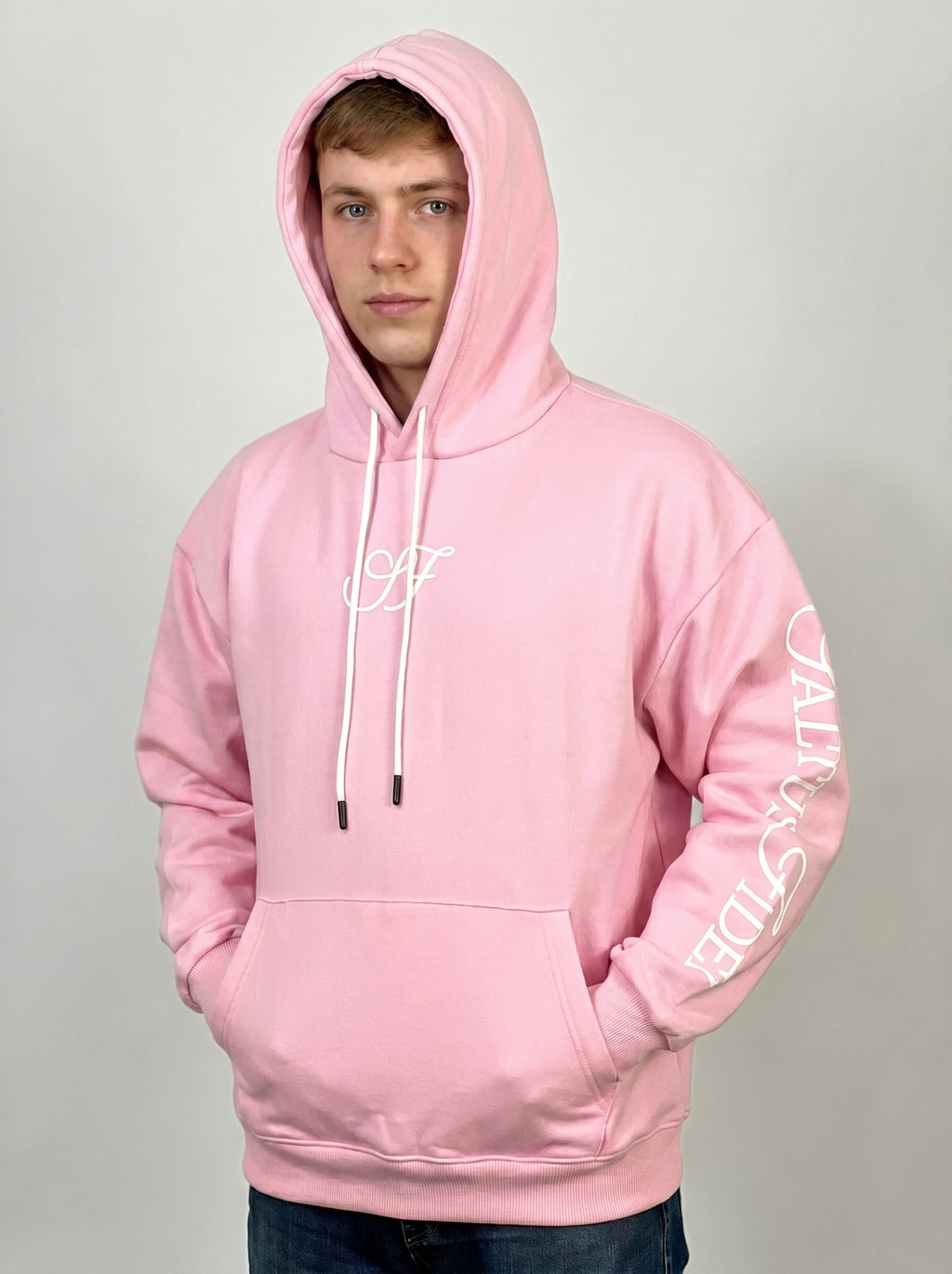 Model wearing the baby pink Saltus Fidei hoodie, studio lifestyle shot
